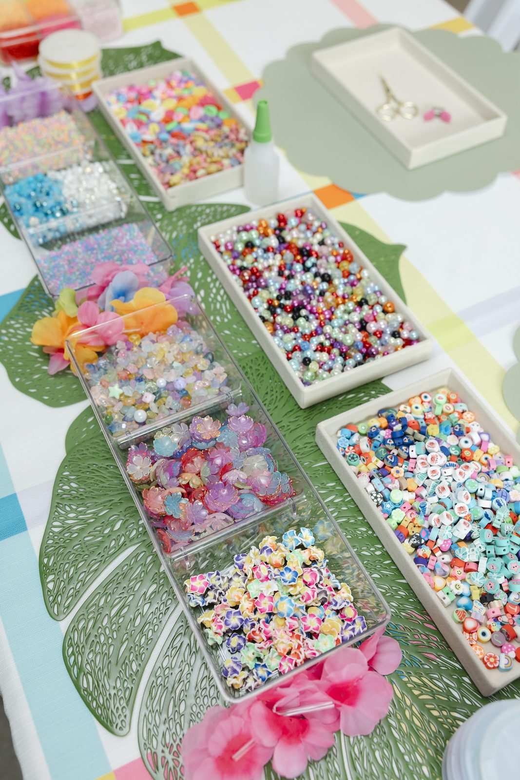 Trays of beads and charms laid out on leaf placemats for a Charm Bar