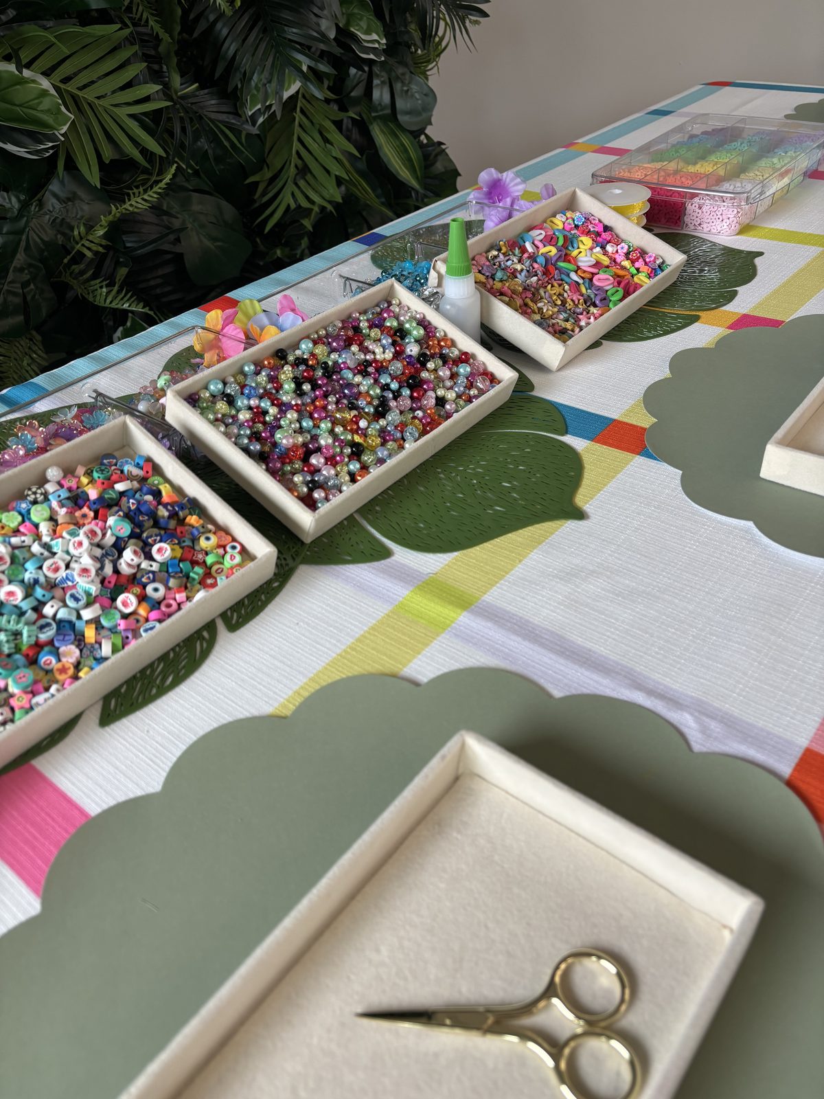 Bead trays and scalloped placemats running the length of a styled Charm Bar table