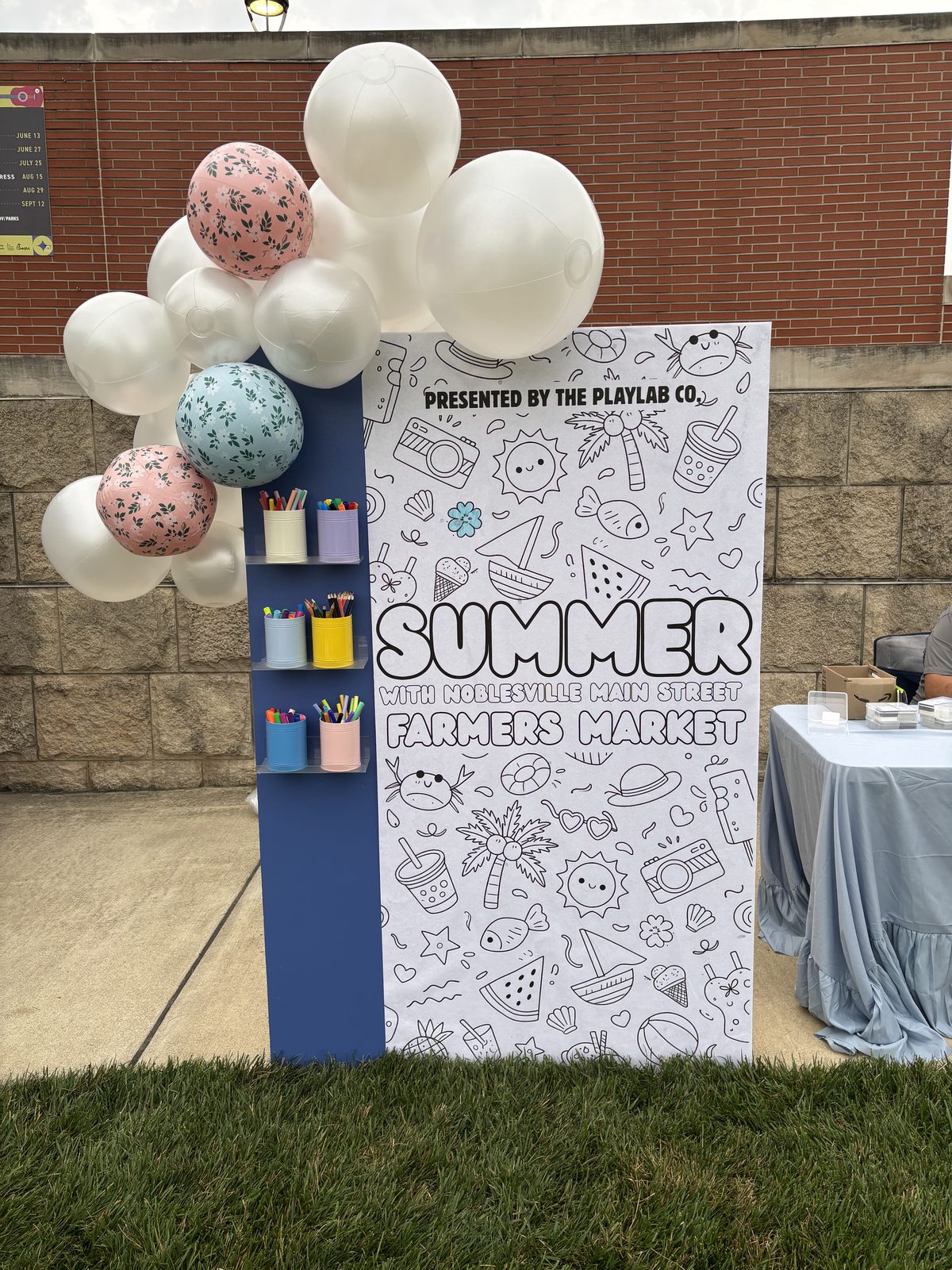 A PlayLab Co. coloring board set up at a summer farmers market