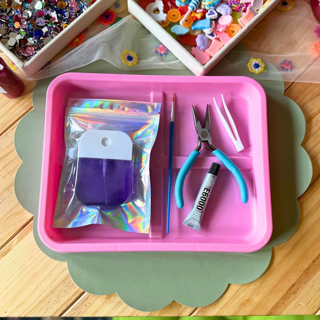 A jewelry making kit with pliers and findings set out on a scalloped tray